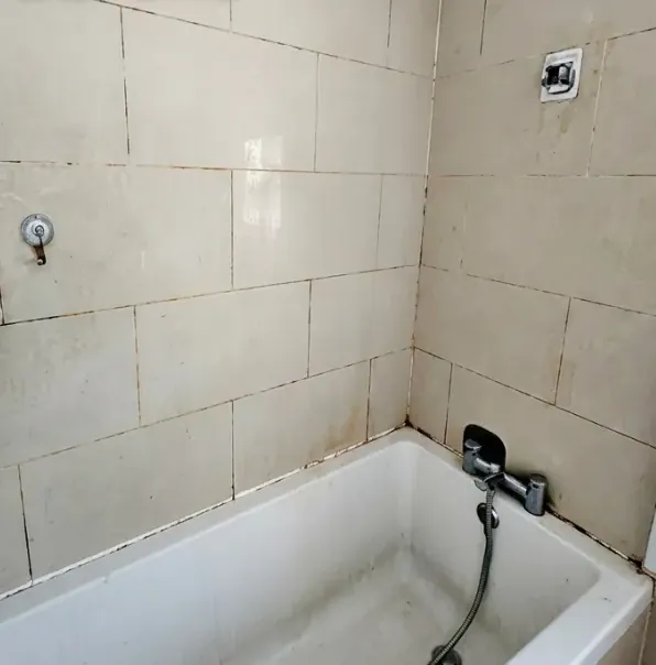 Bathroom tiles before cleaning, with stained grout and limescale