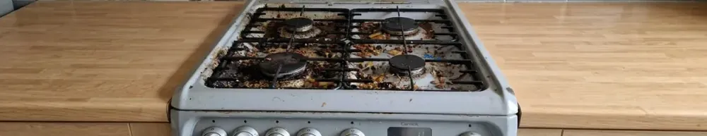 Gas hob before cleaning, covered in burnt-on grease